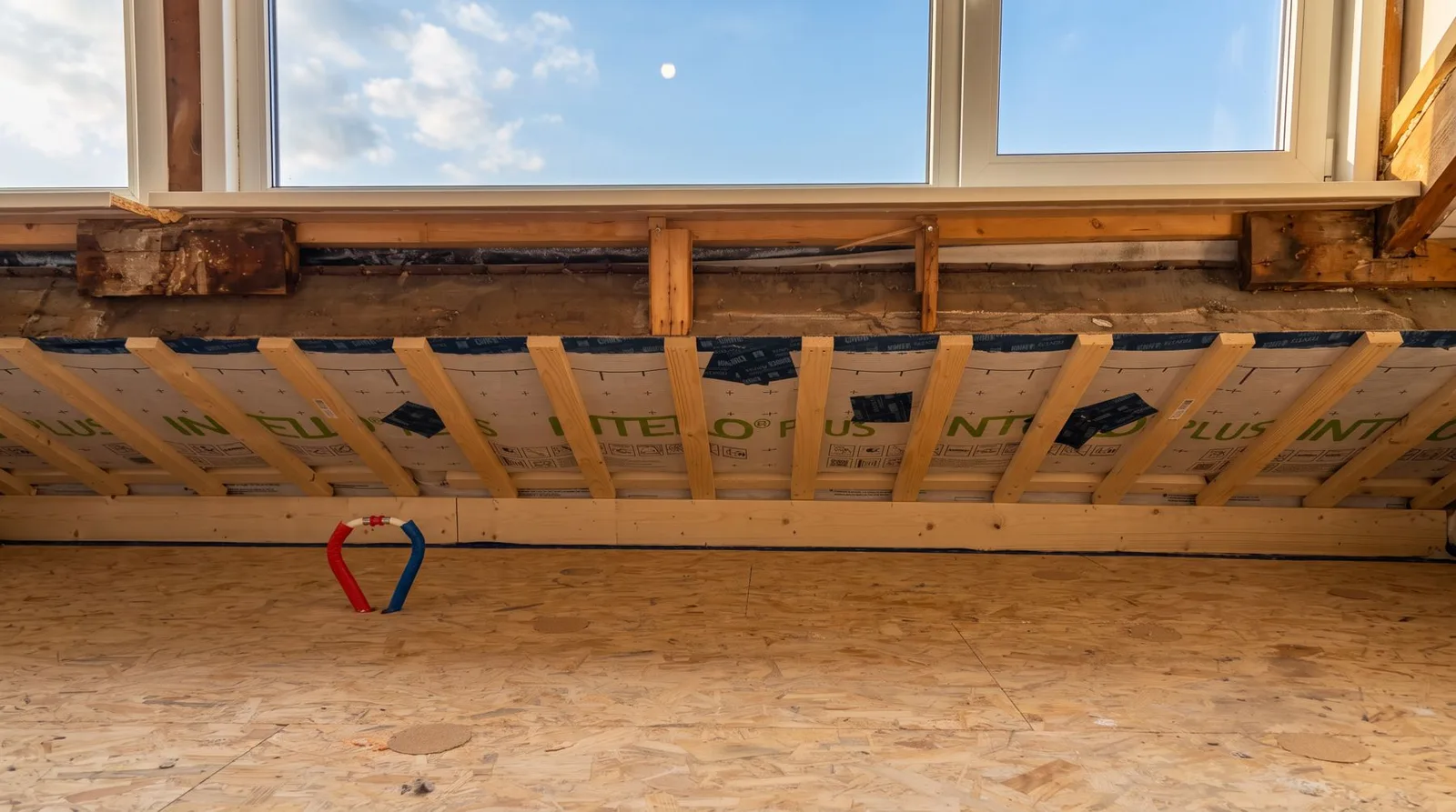 Nieuwe OSB-vloer en afgewerkte knieschotconstructie onder een raam